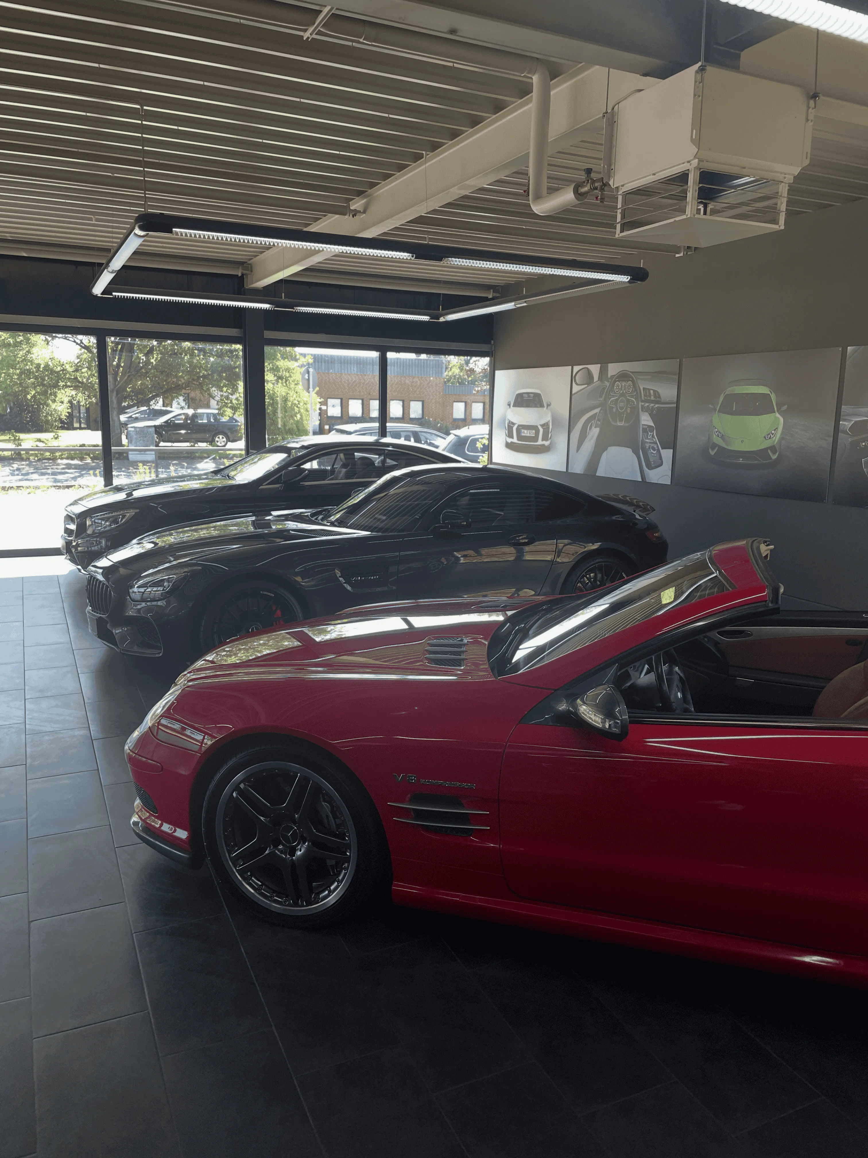 Unser showroom von innen mit einem rotem Fararri und zwei schwarzen mercedes und